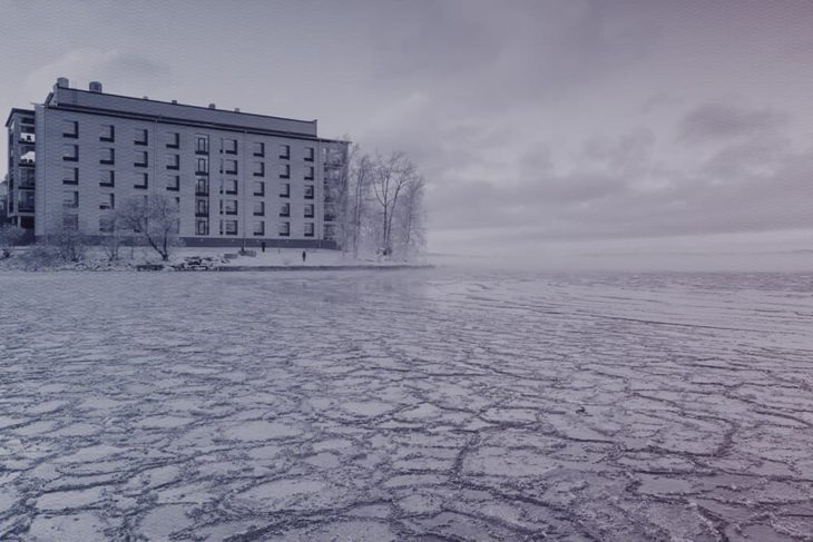 Jäätynyt järvi ja talo taustalla